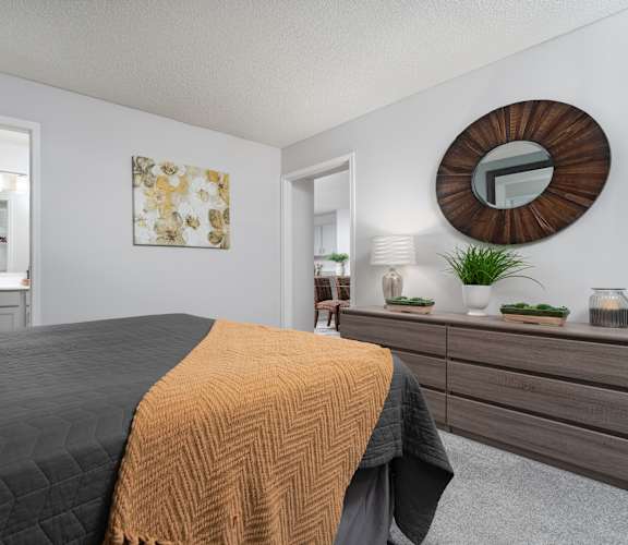 A bedroom with a large bed, a mirror, and a painting on the wall.