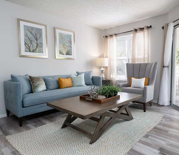 A living room with a blue couch, a coffee table, and two framed pictures on the wall.