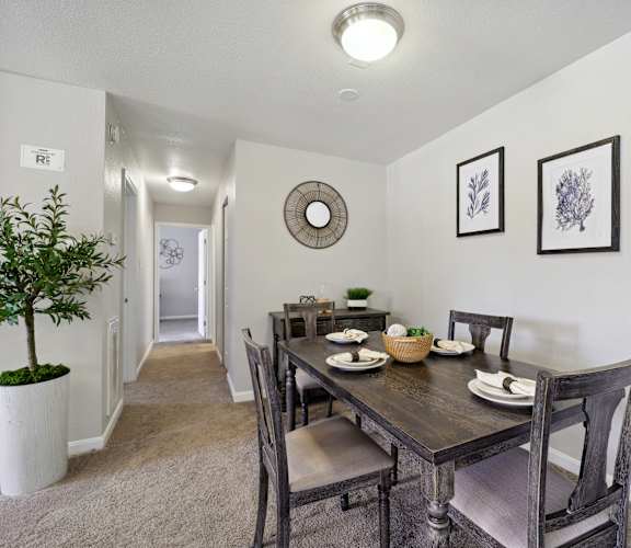 A dining room with a table set for two and a plant in a white pot.