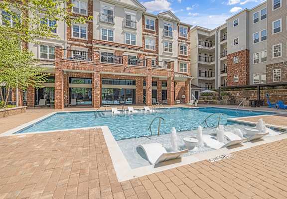 A large outdoor swimming pool with a fountain in the middle of it.
