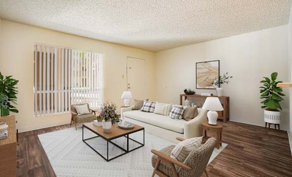 A living room with a white couch, a coffee table, and a potted plant.
