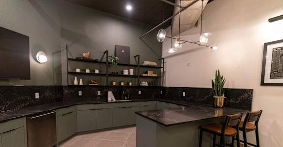 A kitchen with a black countertop and green cabinets.