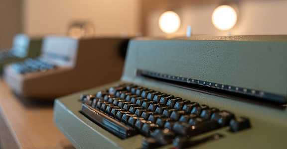 A vintage typewriter is in focus with a blurred background.