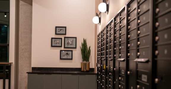 A black cabinet with silver handles is next to a wall with three pictures on it.