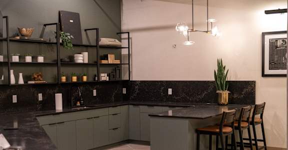 A kitchen with a black countertop and grey cabinets.