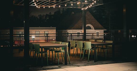 A patio with tables and chairs under string lights.