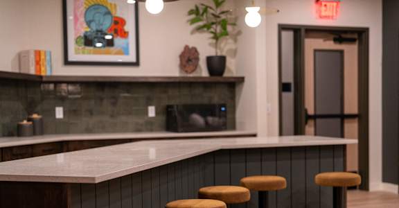 A bar area with a white counter and three stools.