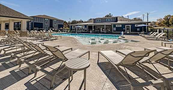 our resort style pool is filled with chaise lounge chairs and tables and our building