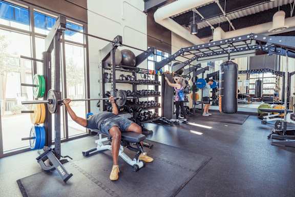 A man is working out in a gym with a barbell.
