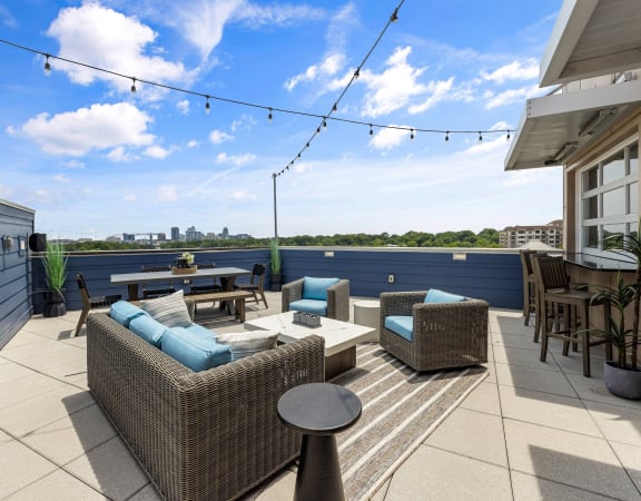 a rooftop patio with wicker furniture and a view of the city