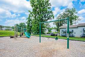 A playground with a green swing set and a green slide.