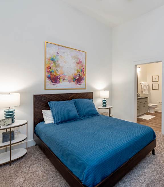 a bedroom with a bed and a bathroom in the background