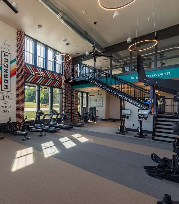 a photo of a gym with cardio equipment and a spiral staircase