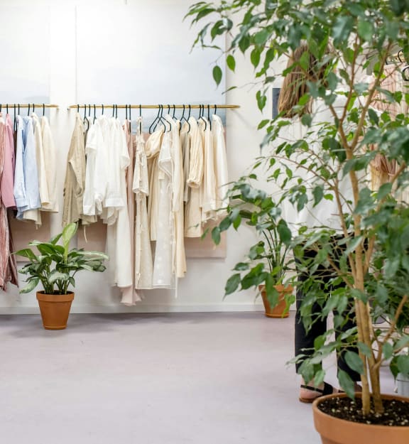 a row of clothes on a rack in a store with plants