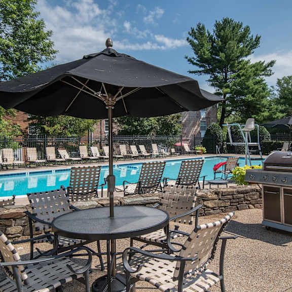 A black umbrella shades a table with chairs around it.