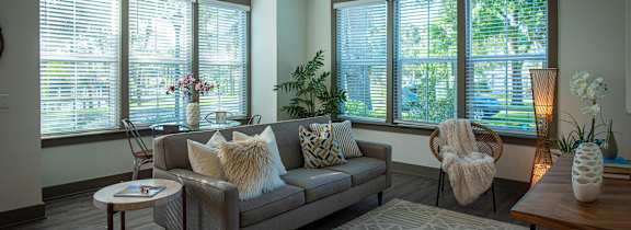 A modern living room with a grey couch and a cowhide rug.