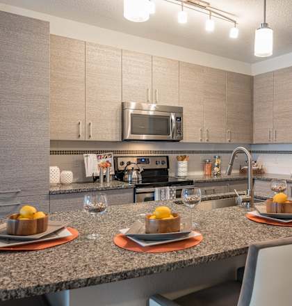 A modern kitchen with a dining table set for two.