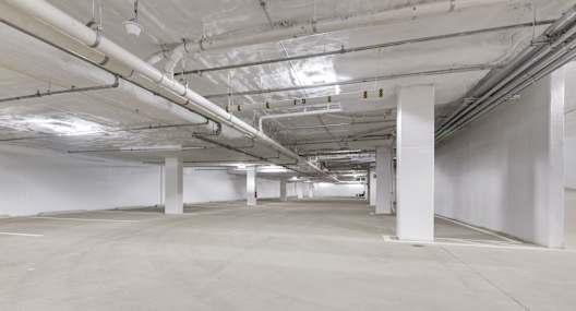 A long hallway with white pillars and pipes on the ceiling.