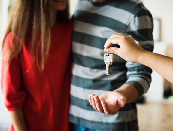 a man and a woman standing in a living room holding keys