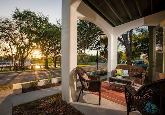 A patio with a chair and a table is in the foreground with a sunset in the background.