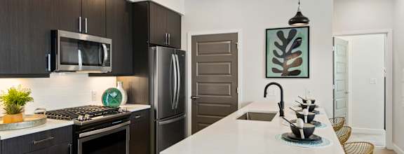 A modern kitchen with dark brown cabinets and a white island.