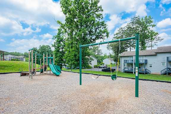 A playground with a green swing set and a green slide.