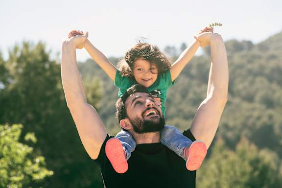 A man lifts a child in the air at Allasso Ranch Apartments, Arizona