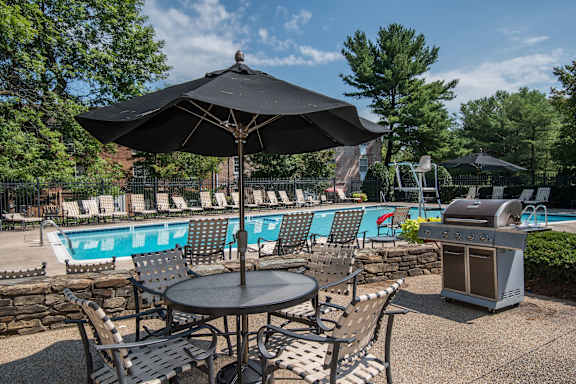 A black umbrella shades a table with chairs around it.