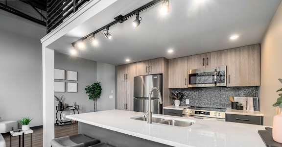 A modern kitchen with a bar area and seating.at Raymond Block, Edmonton Alberta T6E 3R7