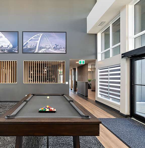 A pool table is in the middle of a room with a couch and a TV.