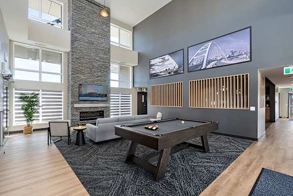 A modern living room with grey furniture and a brick wall.