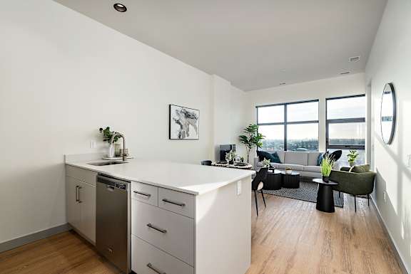 A modern kitchen with a dishwasher, sink, and a green chair.at Raymond Block, Edmonton, T6E 3R7