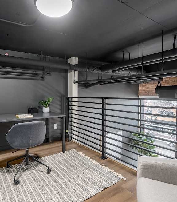 A modern home office with a desk, chair, and a window with blinds.at Raymond Block, Alberta