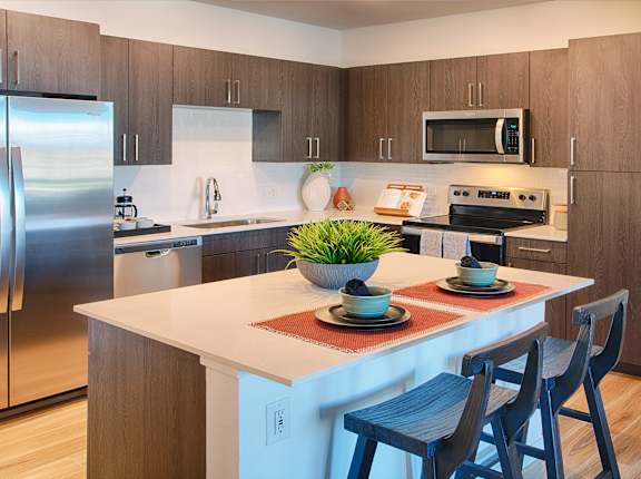 A kitchen with a refrigerator, oven, and sink.