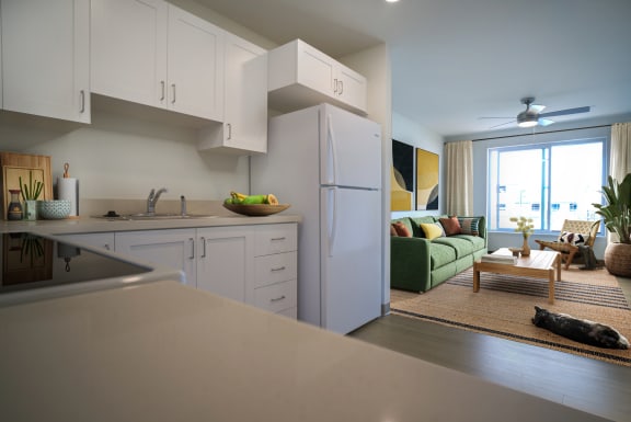 a kitchen with white cabinets and a living room with a green couch