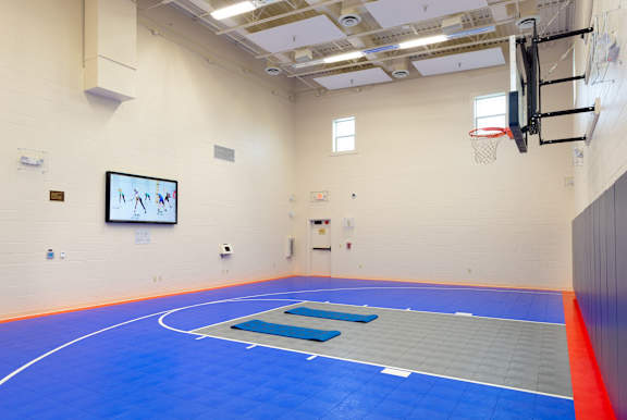 A gym with a basketball hoop and a blue mat.