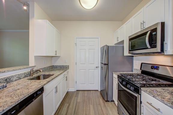 a kitchen with granite countertops and stainless steel appliances at Broadlands Apartments in Ashburn, VA