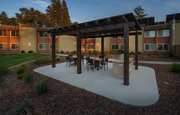 An outdoor dining area with tables and chairs at Sierra Sunrise Senior Apartments