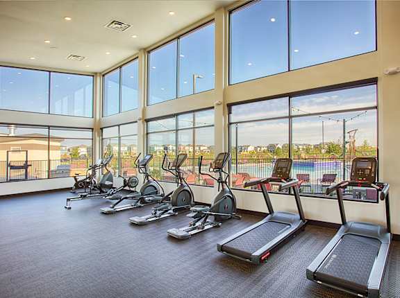 A gym with treadmills and a view of the pool outside.