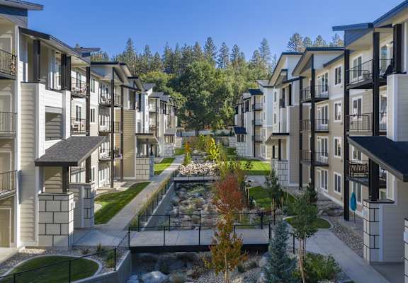 A row of modern townhouses with a small garden in the middle.