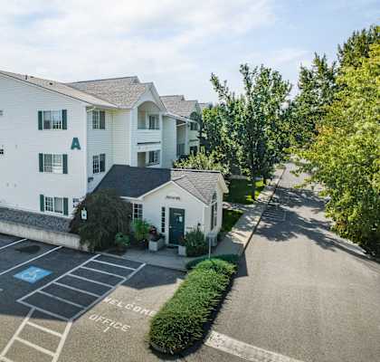 a large white apartment building with a parking lot and a driveway