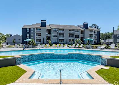 A large swimming pool in front of a multi-story apartment building.