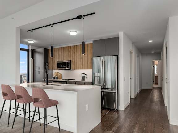 a kitchen with a large island with bar stools and a refrigerator