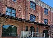 Thumbnail 2 of 16 - A red brick building with a flower bed in front of it.