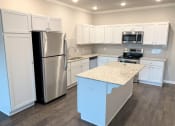 Thumbnail 17 of 60 - B2 (2-car) Kitchen with island, granite countertops, stainless steel appliances, white cabinets