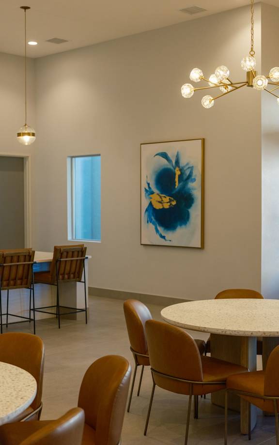 A room with a white table surrounded by chairs and a painting on the wall.
