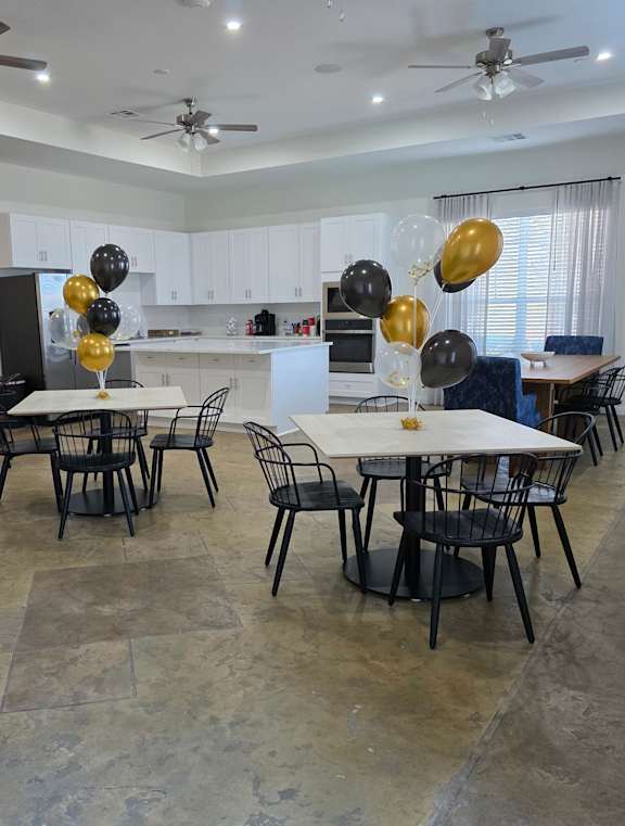 A dining room with a table surrounded by chairs and balloons.