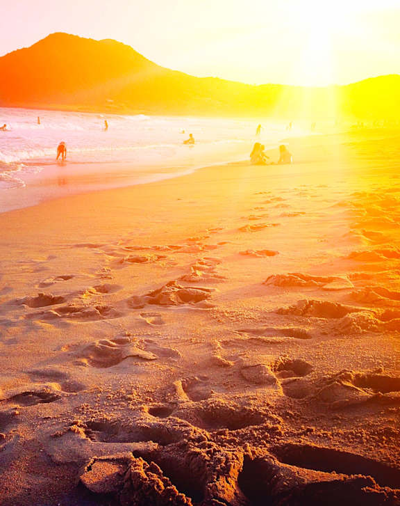 A beach scene with people enjoying the sunset.