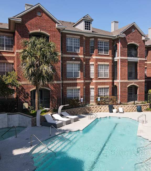 A large brick building with a pool in front.