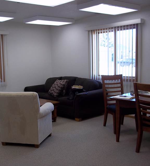A yellow mug sits on a coffee table in front of a grey couch with a yellow pillow and a white blanket.